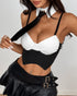 Woman posing in black pinstripe corset top with white bust cups, necktie, and pleated leather mini skirt.