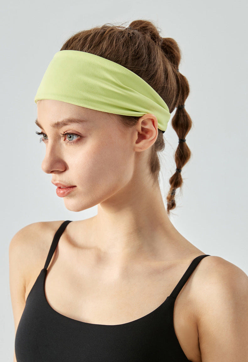 Woman wearing a wide pixie green headband and black sports top in side profile.