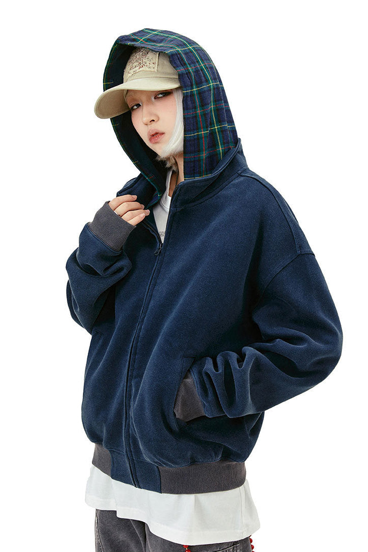 Three-quarter view of the navy hoodie showing green plaid hood lining and ribbed hem