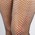 Front view of a curvy model wearing small-mesh black fishnet tights with heels