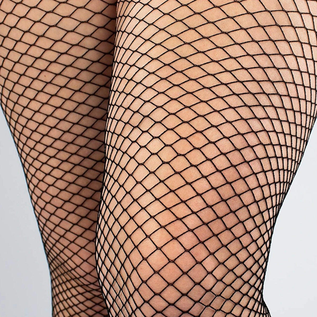 Front view of a curvy model wearing small-mesh black fishnet tights with heels