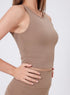Close-up side view of woman wearing quicksand sleeveless workout tank with ruched sides and matching leggings.