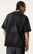Back view of black oversized T-shirt with no visible design, worn by model with braids.