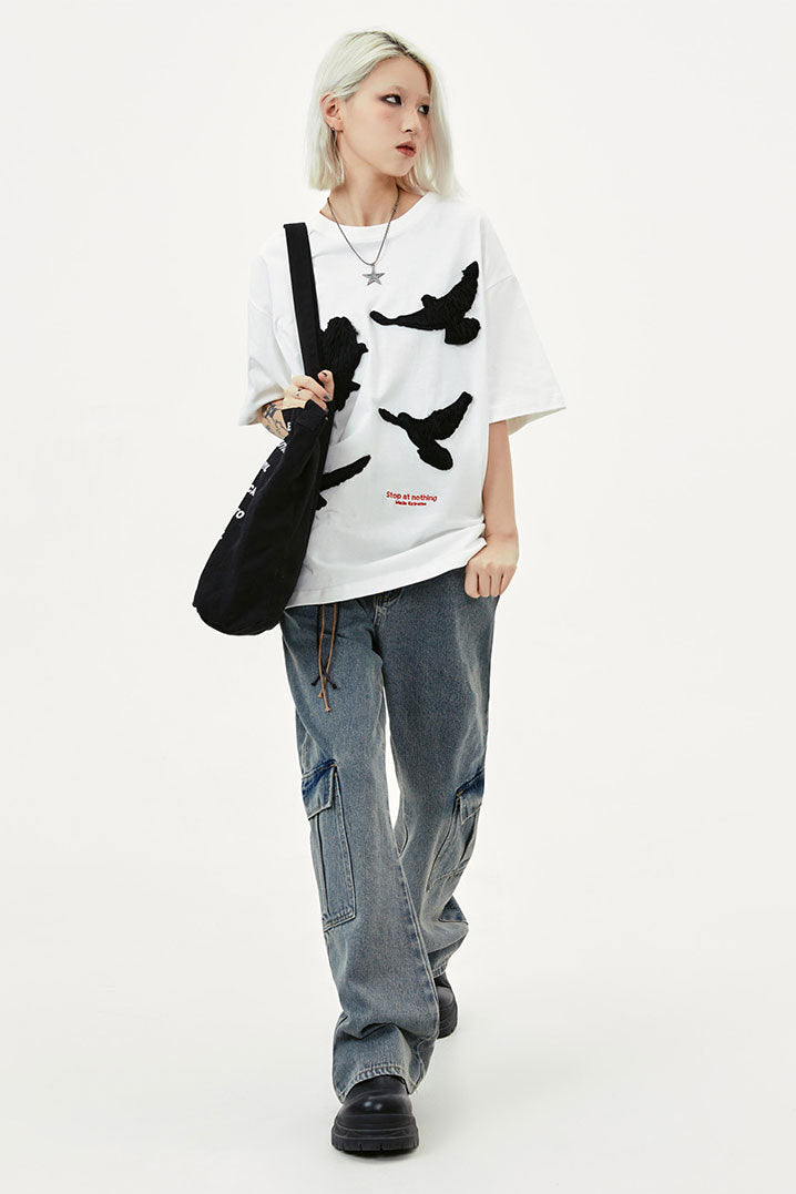 White raised dove embroidered oversized T-shirt styled with baggy cargo jeans and black platform shoes