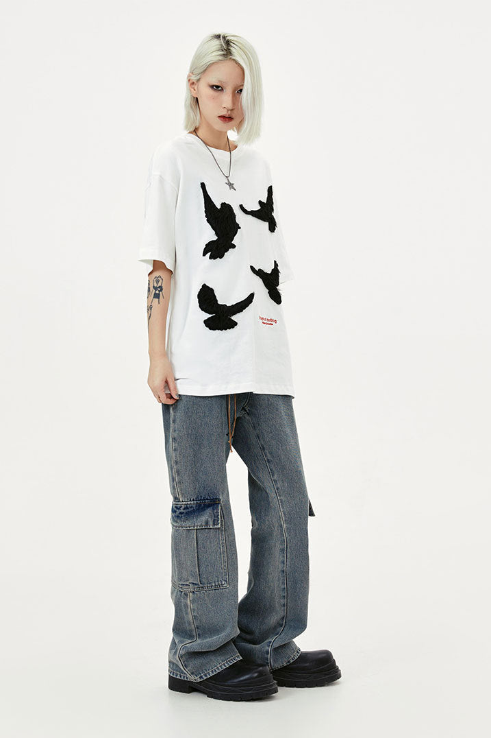 Three-quarter view of white short-sleeve T-shirt showing scattered black dove embroidery