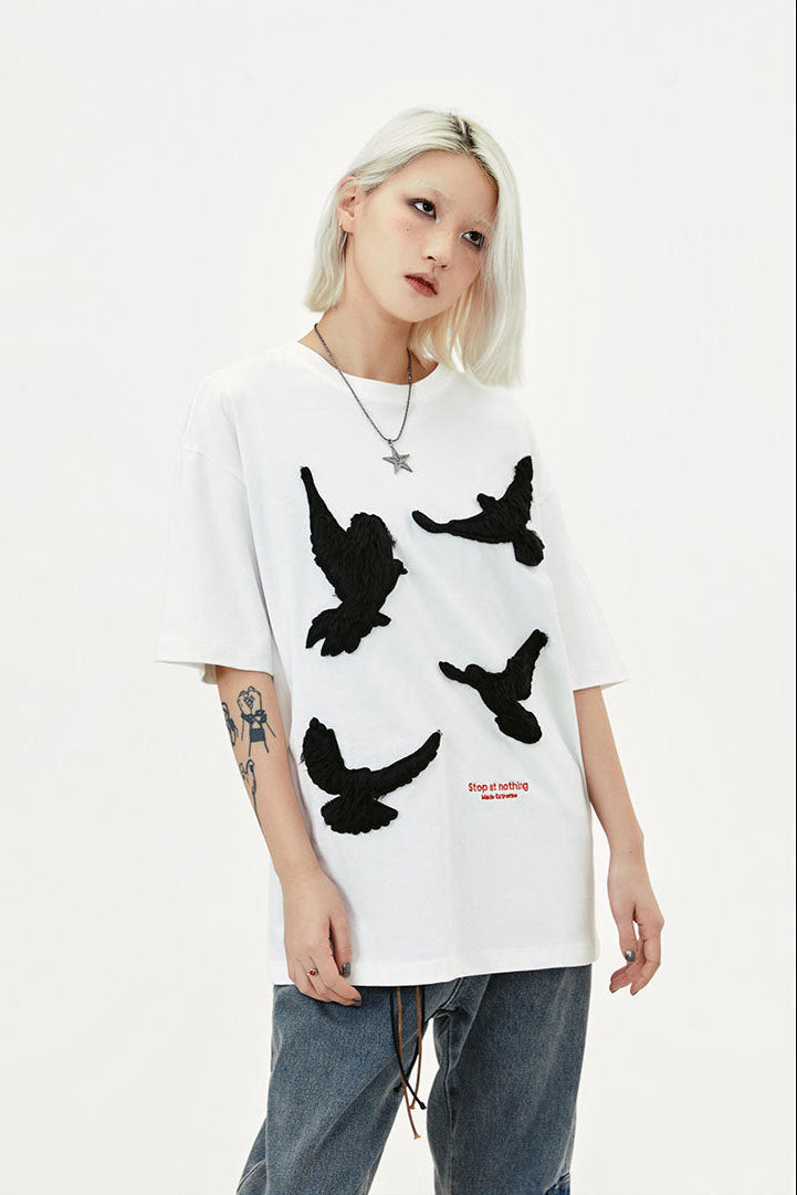 Close front view of white T-shirt with textured black dove motifs and small red text embroidery