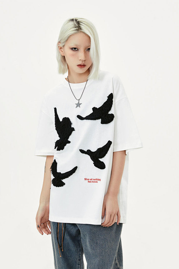 White oversized T-shirt styled with washed blue cargo jeans, star necklace, and black shoes
