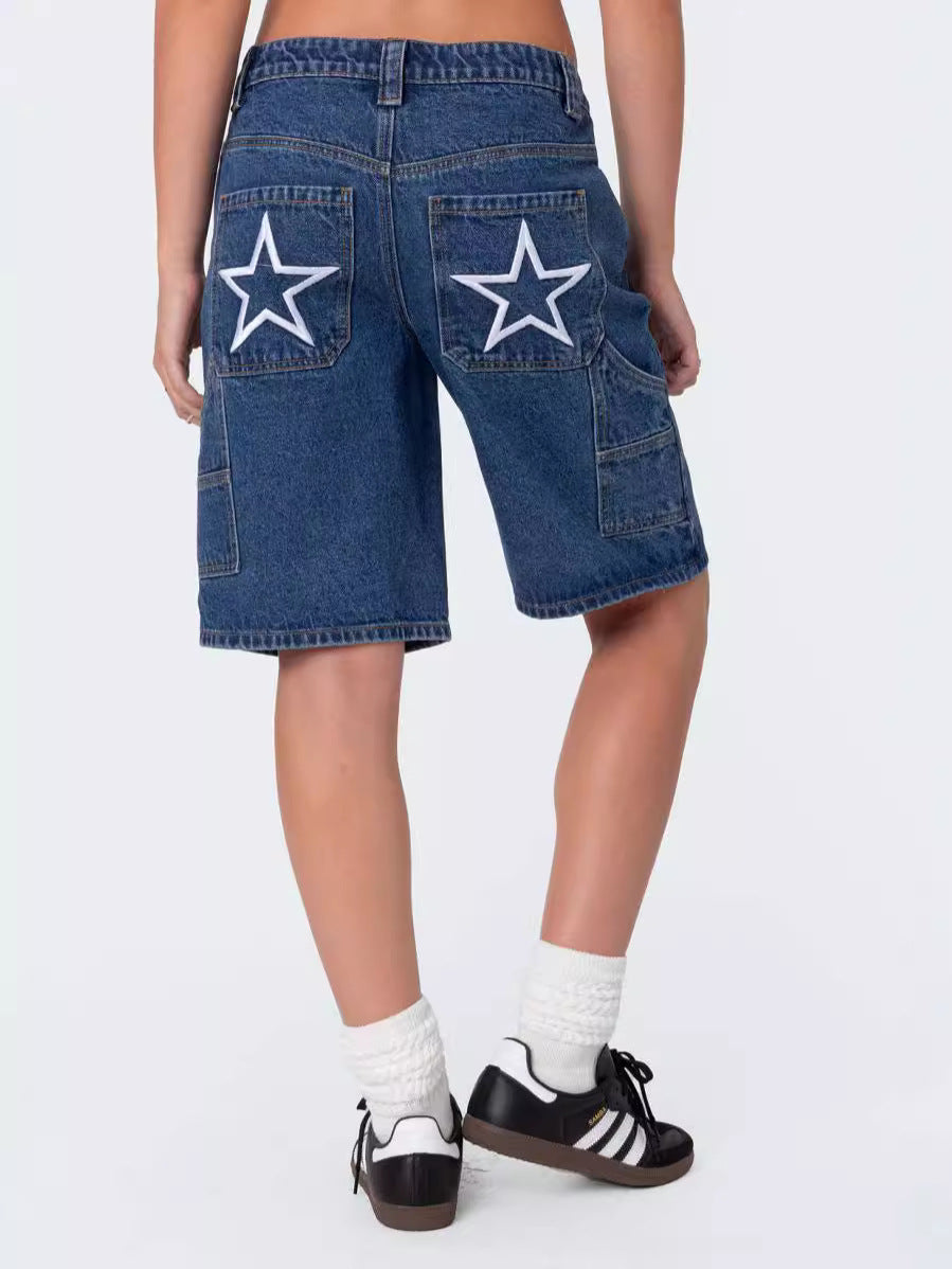 Back view of woman in dark wash denim shorts featuring white star patches, styled with sneakers and socks.