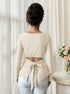 back view showing tie-back opening and peplum flare on cream ribbed long sleeve top