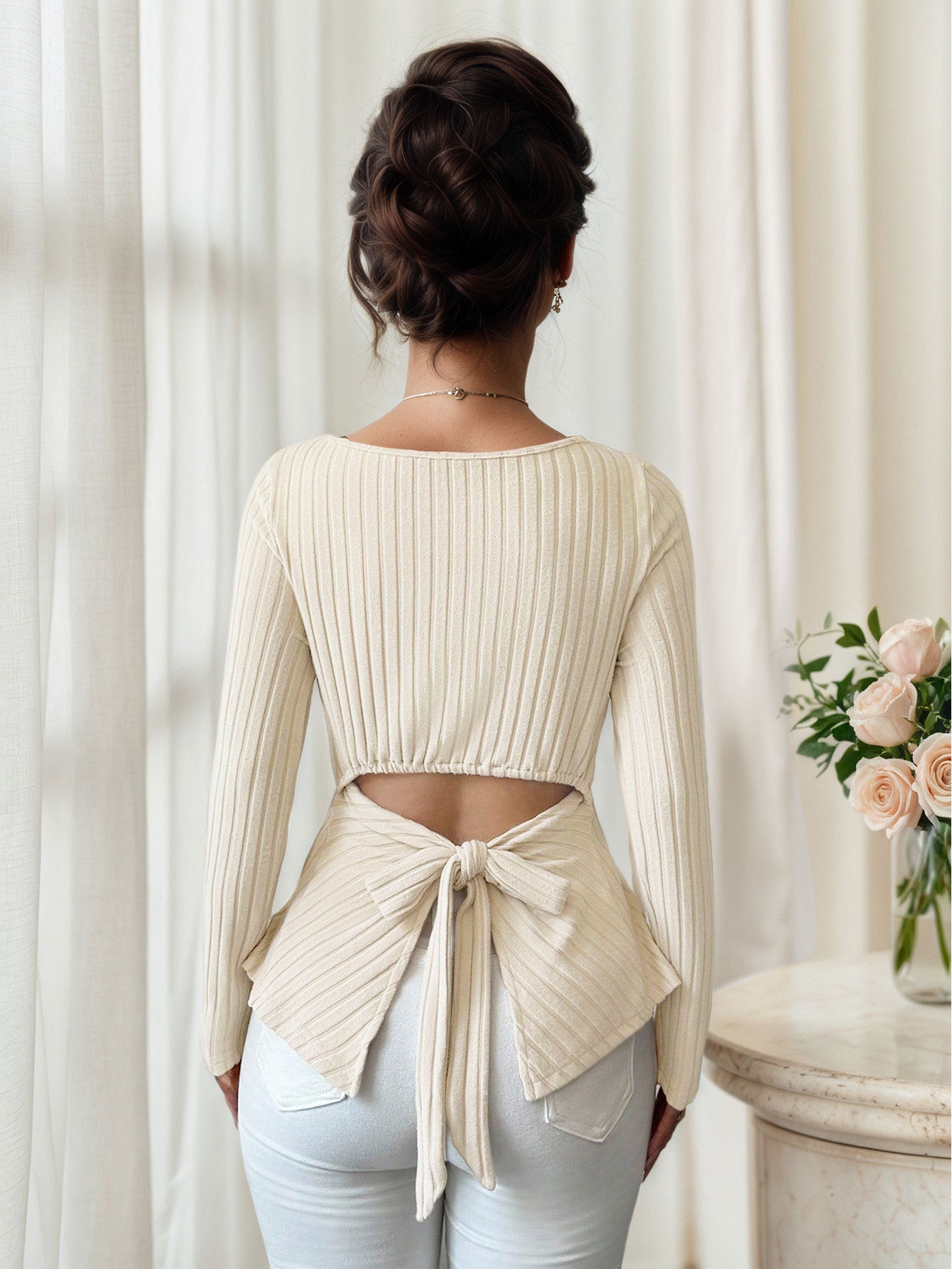back view showing tie-back opening and peplum flare on cream ribbed long sleeve top