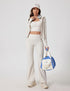 Model in white ribbed athletic yoga jacket with matching flare pants