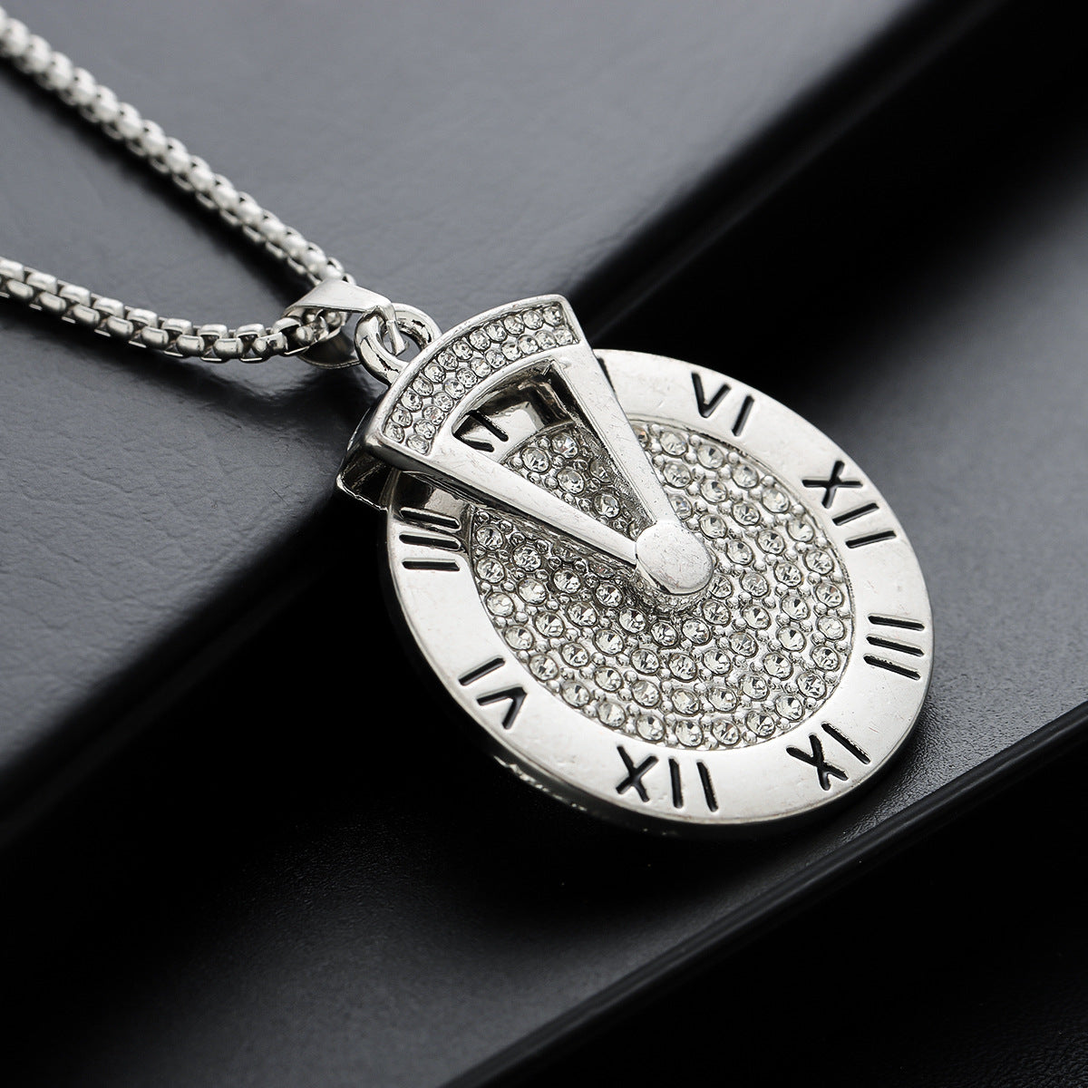 Close-up of silver Roman numeral pendant  with engraved details.
