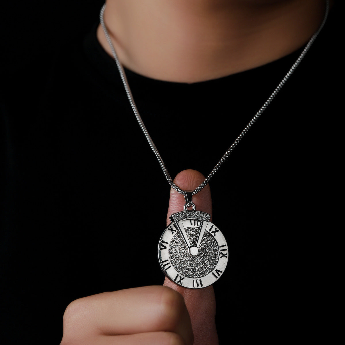  Hand holding Roman numeral pendant showing engraved detail.