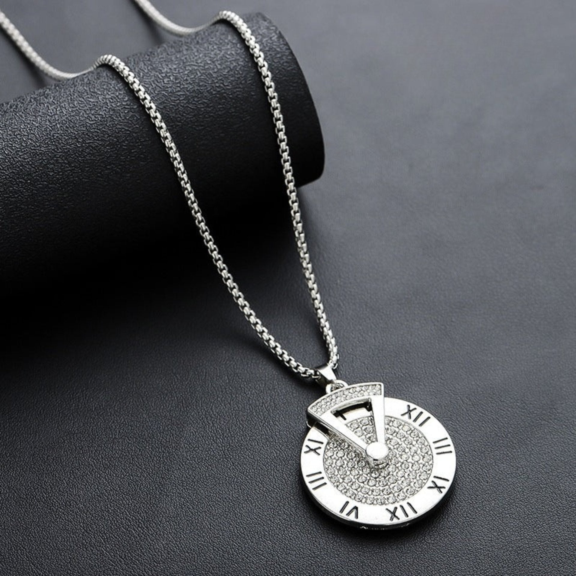 Silver Roman numeral pendant necklace styled on black textured roll.