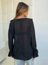 Back view of black sheer blouse with flowy sleeves and relaxed fit.