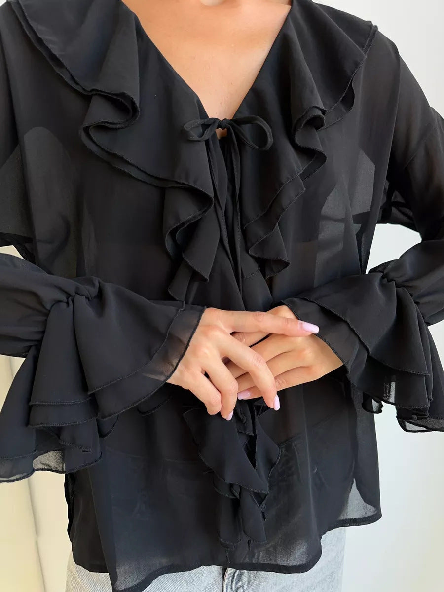Close-up of black blouse sleeve and front tie with soft ruffled edges.