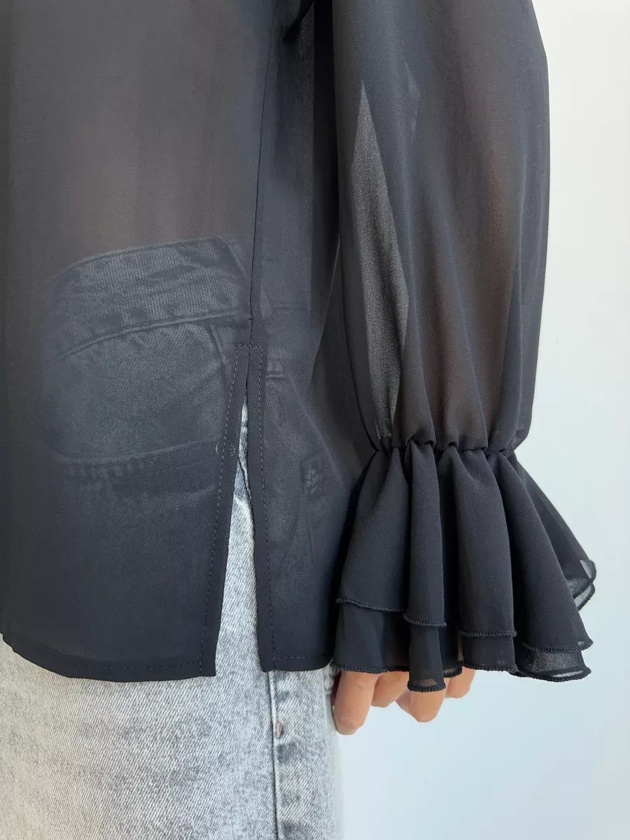 Side view of black blouse hem with slit and ruffled sleeve