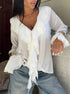 Ruffled white blouse with V-neck and layered sleeves styled with light jeans.