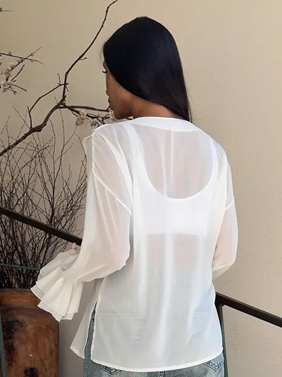 Back view of sheer white long sleeve blouse with flared cuffs.