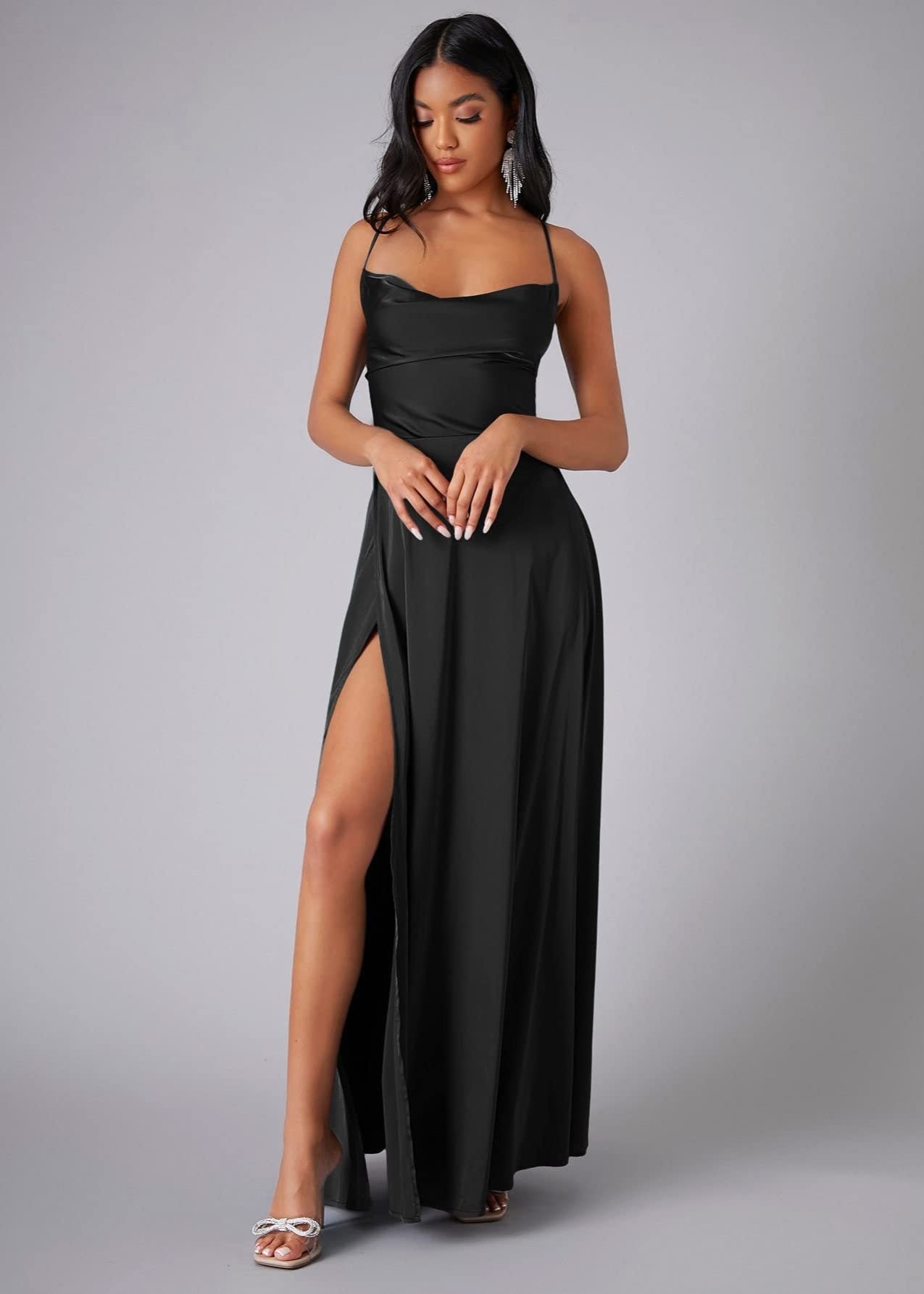 Woman wearing a black evening gown with a slit on a gray background