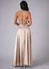 Back of woman wearing a champagne  evening gown with a backless design on a gray background