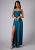 Woman wearing a haze blue evening gown with a slit on a gray background
