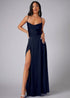 Woman wearing a navy evening gown with a high slit on a gray background