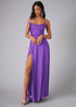 Woman wearing a purple prom dress with a slit on a gray background