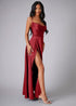 Side view of woman wearing a red evening gown with a slit on a gray background