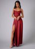 Woman wearing a red prom dress with a slit on a gray background