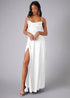 Woman wearing a white prom dress with a slit on a gray background
