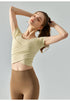 Beige cropped yoga top with sculpted seams and fitted short sleeves.