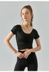 Black short sleeve yoga top with sculpting cross-pleat detail and cropped cut.