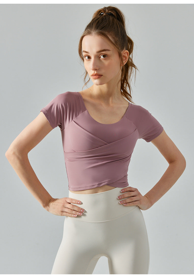 Oriental pink short sleeve yoga top with cropped silhouette and sculpting pleats.