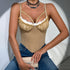 Woman in beige corset with lace detail and jeans, draped in white blazer.