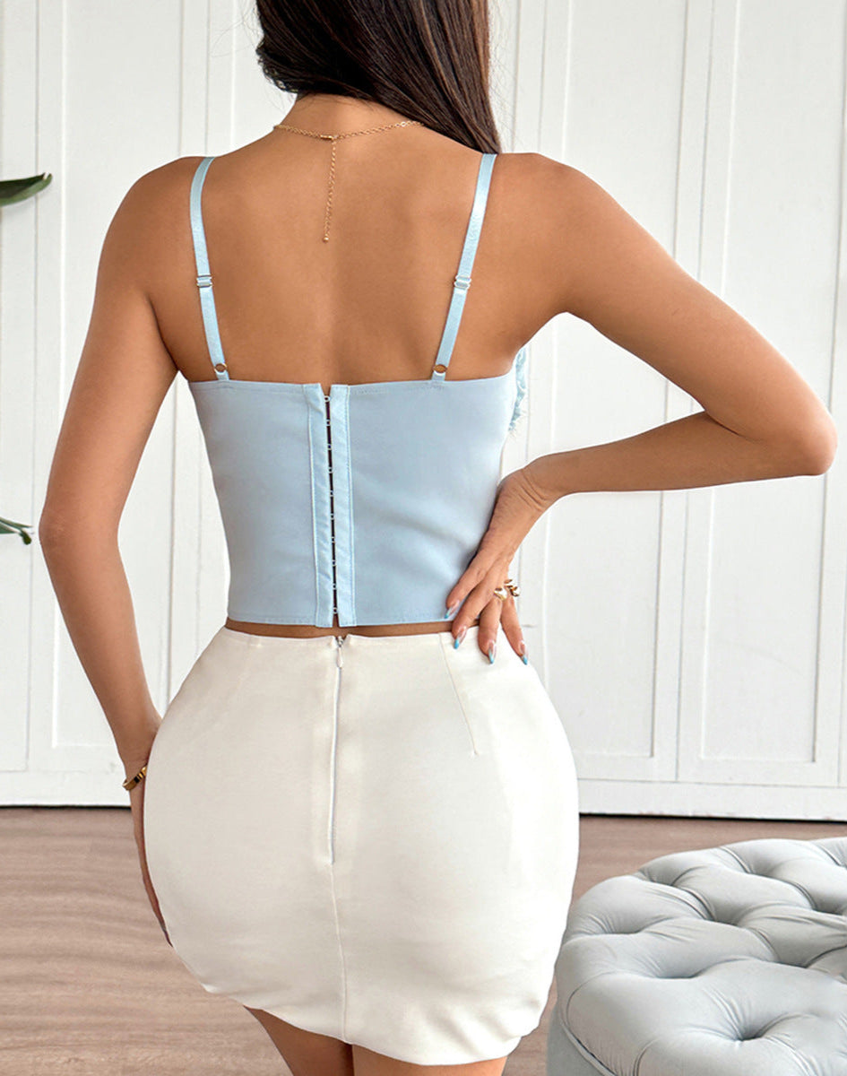 Back view of woman in light blue corset top and white skirt showing zipper detail.