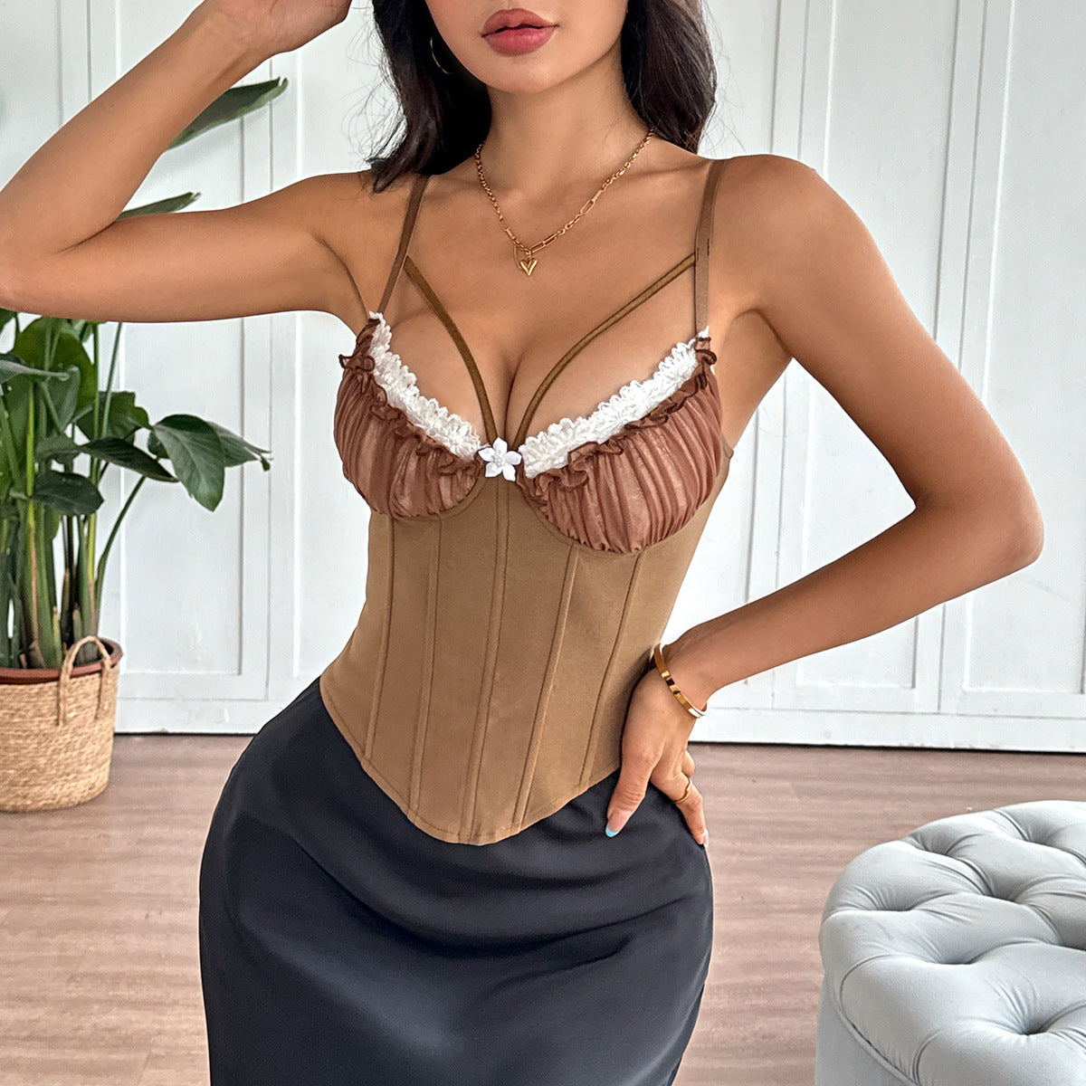 Woman in brown corset top with sheer ruffled cups and white lace trim paired with black satin skirt.