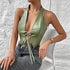 Woman seated in sage green halter PU corset top and denim jeans.
