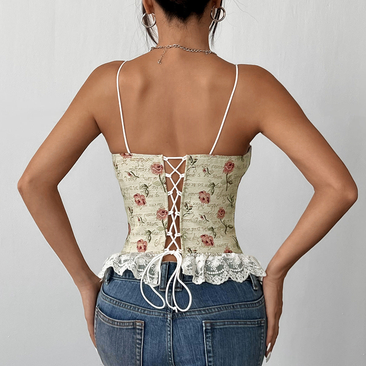 Back view of floral corset top with lace-up closure and lace hem, styled with denim.