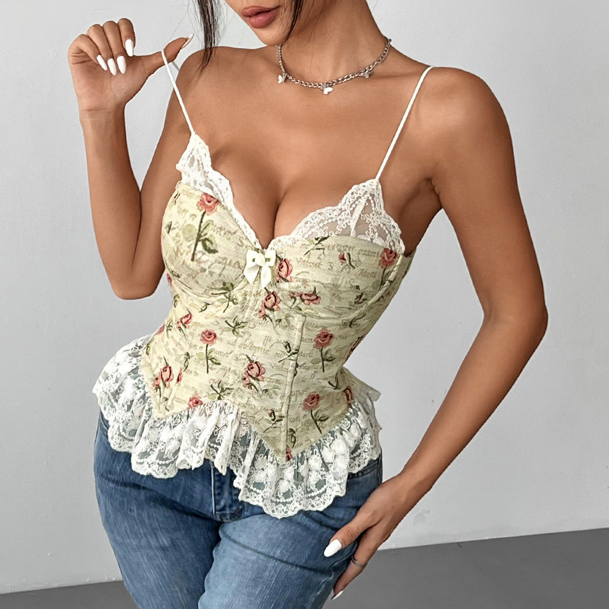 Woman poses in floral jacquard corset with lace neckline and hem, paired with jeans.