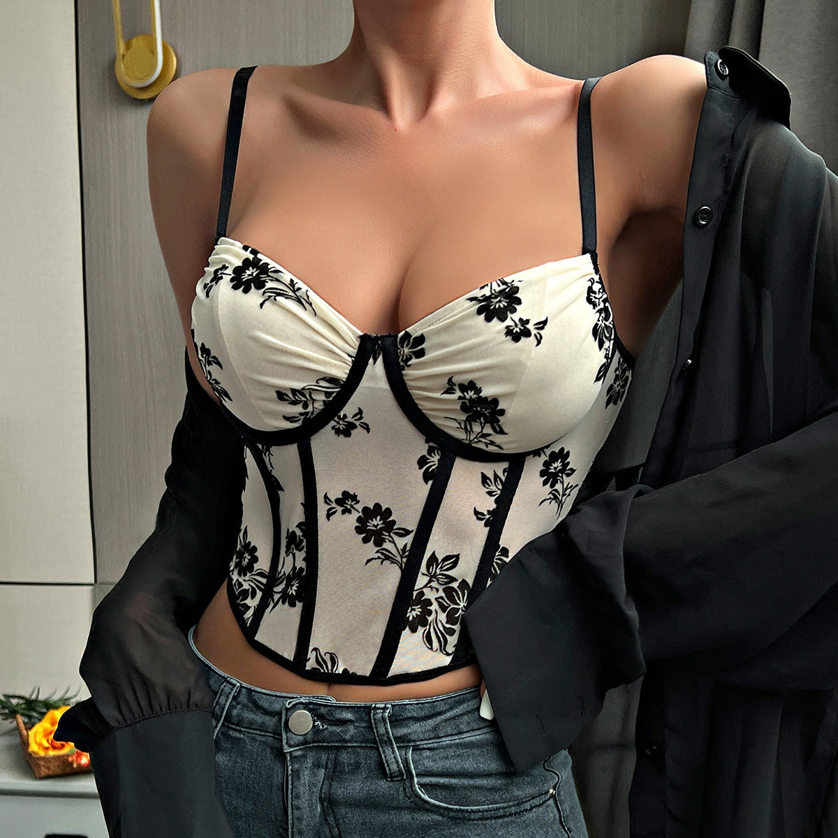 Woman styles cream floral corset with black shirt draped off shoulders.
