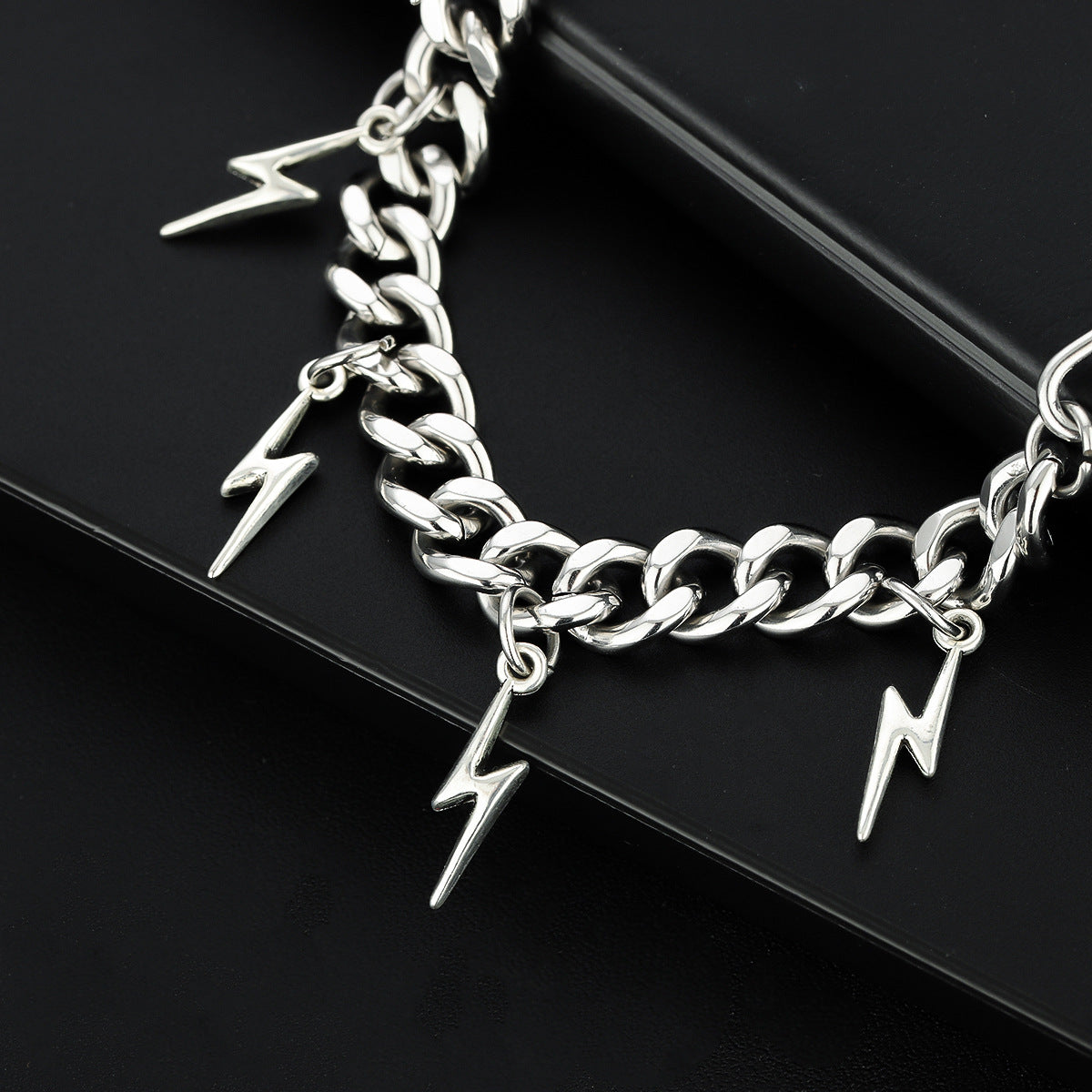 Close-up of lightning bolt charms on chunky silver bracelet.