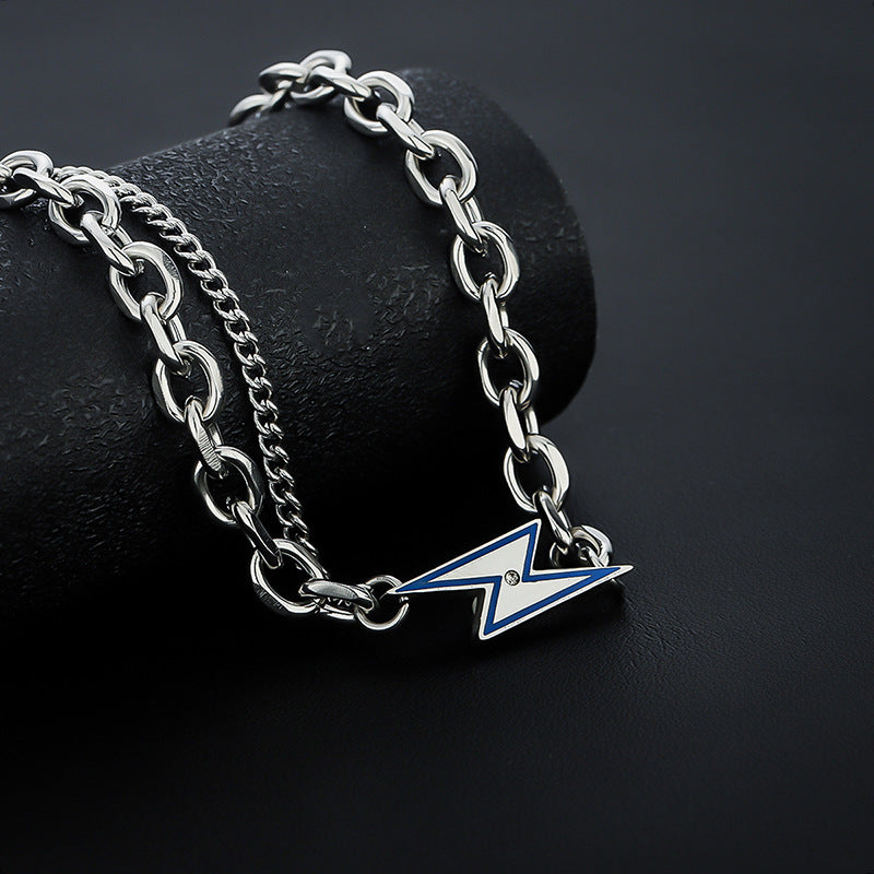 Silver lightning bolt chain necklace draped over black textured cylinder.