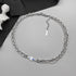 Mixed-link silver chain necklace with blue detail on gray background.