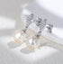 Silver-tone pearl drop earrings, diamond-shaped studs, close-up
