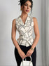 Woman wearing sleeveless printed summer top with white pants and bag