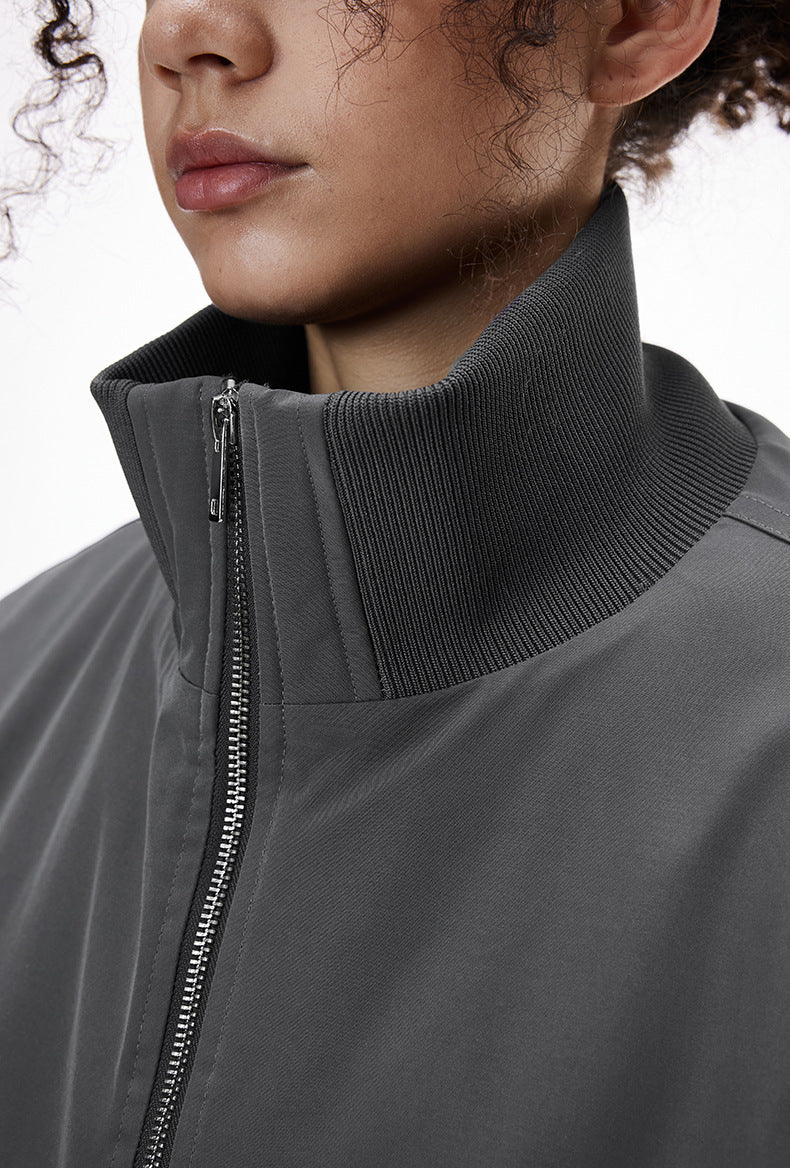 Close-up of a person wearing a gray bomber jacket with collar stand detail