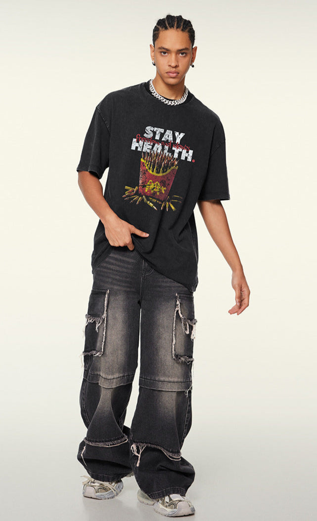 Model stands with one hand in pocket, wearing black T-shirt featuring satirical bullet fries design