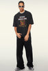 Model in black streetwear tee and loose black pants styled with chain necklace and shades.