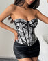 Woman facing forward in floral jacquard corset with exposed boning and black trim.